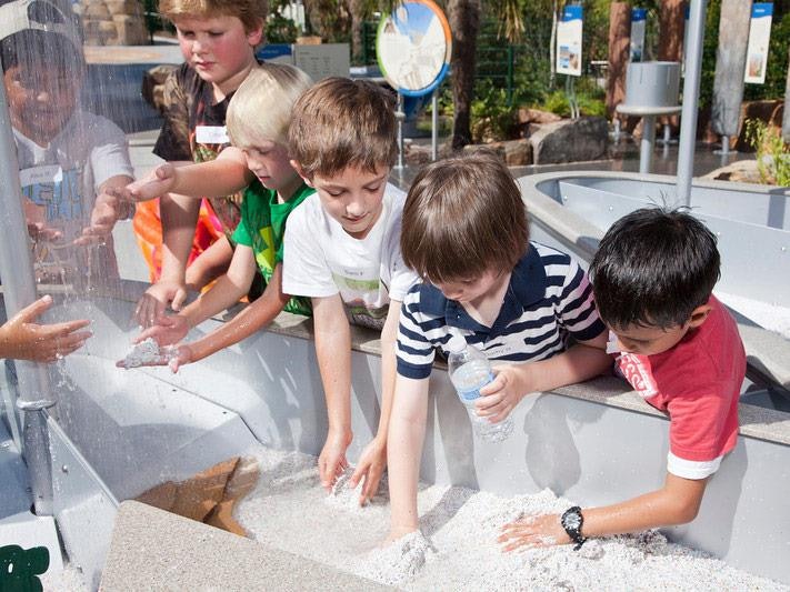 Children with their hands in the water at an interactive exhibit