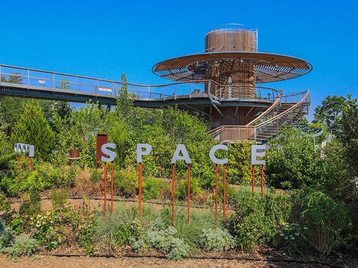signage that says space in front of a large climbing tower